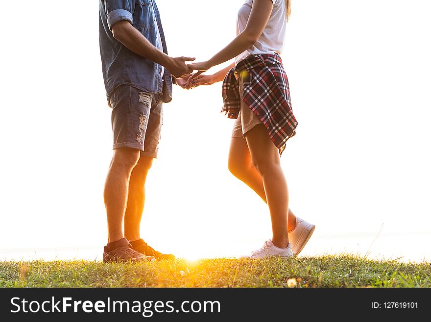 Romantic date outdoors. Young couple in love walking in the autumn park holding hands looking in the sunset