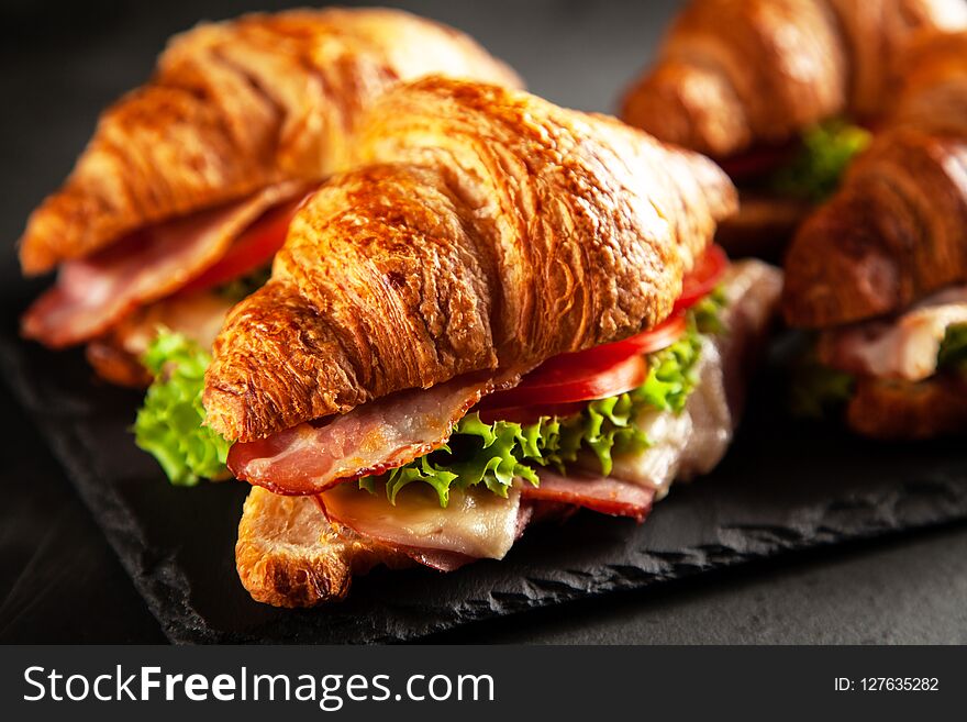 Classic BLT croissant sandwiches on dark background
