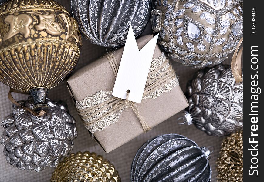 From above shot of golden and silver baubles lying around lovely gift box with empty tag. From above shot of golden and silver baubles lying around lovely gift box with empty tag.