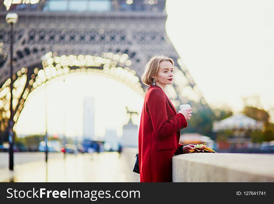 Beautiful young French woman drinking coffee near the Eiffel tower in Paris on a fall or spring day. Beautiful young French woman drinking coffee near the Eiffel tower in Paris on a fall or spring day