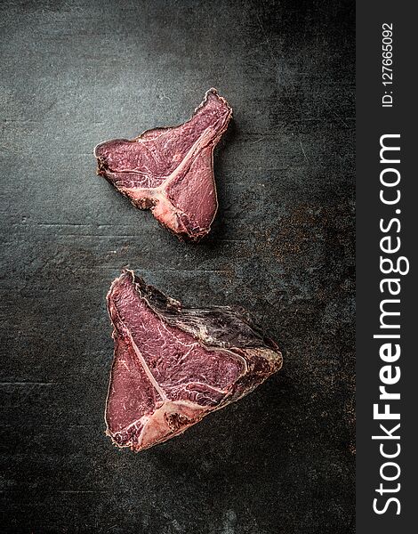 Close-up raw T-bone steak on black cutting board