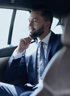 Smiling Business Man Sitting In The Back Seat Of A Car Stock Photography