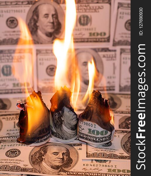 A hunred dollar bill in American US currency is on fire. A hunred dollar bill in American US currency is on fire