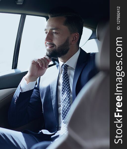 Smiling business man sitting in the back seat of a car
