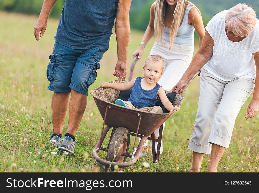 Family Pushing Their Small Child In A Wheelbarrow