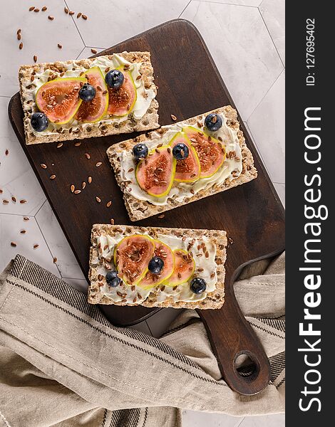 Canape or crostini with multigrain crispread with cream cheese and fig jam on a slate board. Delicious appetizer ideal as an aperitif. Canape or crostini with multigrain crispread with cream cheese and fig jam on a slate board. Delicious appetizer ideal as an aperitif.