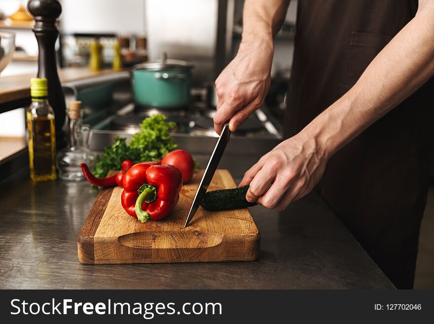 Close up of a man hands chopping vegetables on a cutting board at he kitchen