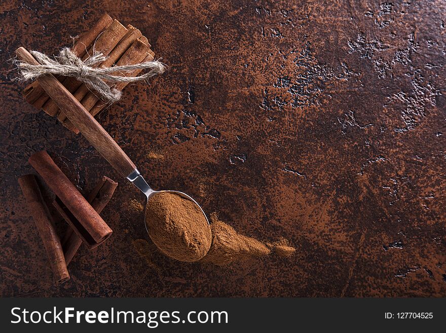 Cinnamon Sticks And Powder In Spoon On A Old Copper Table .