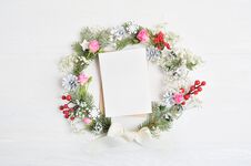 Mockup Of Christmas Wreath With Sheet Of Paper Decorated With Red Berries, Cones And Roses. On Wooden Background Royalty Free Stock Images