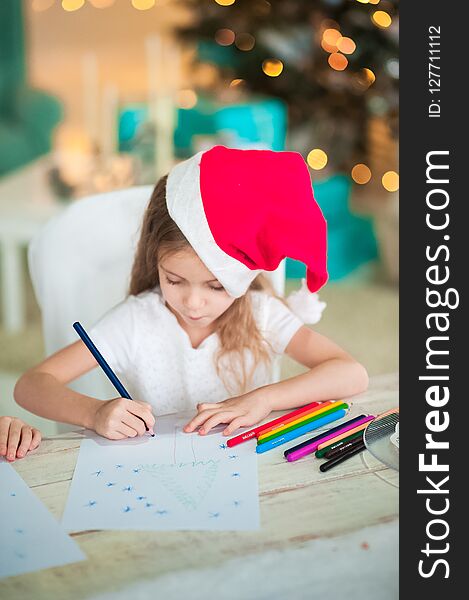 The girl writes a letter to Santa Claus for the New Year.