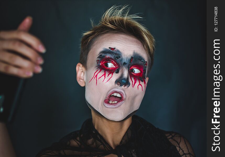 A girl makes selfie in makeup for Halloween.