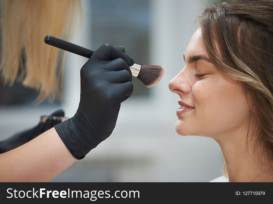 Selective focus of client getting professional makeup in beauty salon