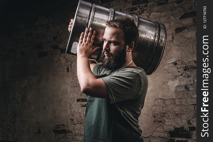 Brewer in apron holds barrel with craft beer at brewery factory.
