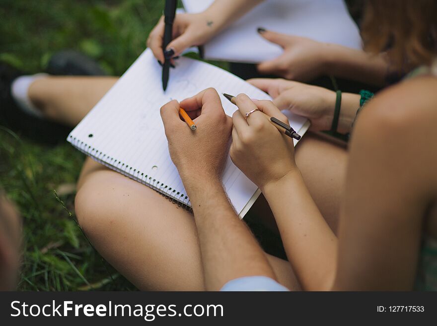 Groupmates do their homework. A girl writes down the solutions. Students hold the pens and pencil and explaining each other the task. Groupmates do their homework. A girl writes down the solutions. Students hold the pens and pencil and explaining each other the task.