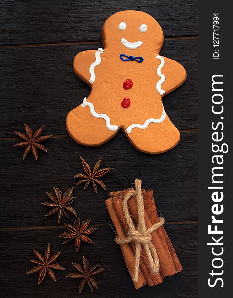 Vertical format photograph of a gingerbread man cookie. On a black wooden background. With star anise and cinnamon stick tied together with twine. Vertical format photograph of a gingerbread man cookie. On a black wooden background. With star anise and cinnamon stick tied together with twine.