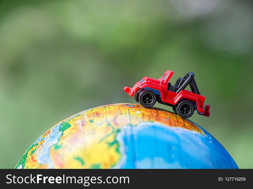 A car on globe on green background. Miniature car toy on globe. Travel concept