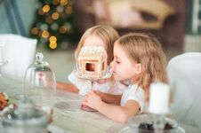 Twin Sisters At A Table In The Kitchen Playing With A Ginger House For The New Year. The Kitchen In Bright Colors Is Decorated Stock Photography Twin Sisters At A Table In The Kitchen Playing With A Ginger House For The New Year. The Kitchen In Bright Colors Is Decorated Stock Photography