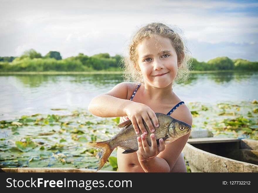 In The Summer Of Bright Sunny Day A Little Girl On The River Caught A Large Bream.