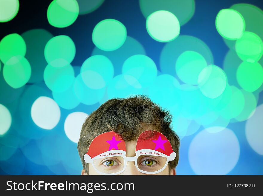 Portrait of cheerful, attractive man on blue background with copy space for text, look over christmas glasses. Portrait of cheerful, attractive man on blue background with copy space for text, look over christmas glasses.