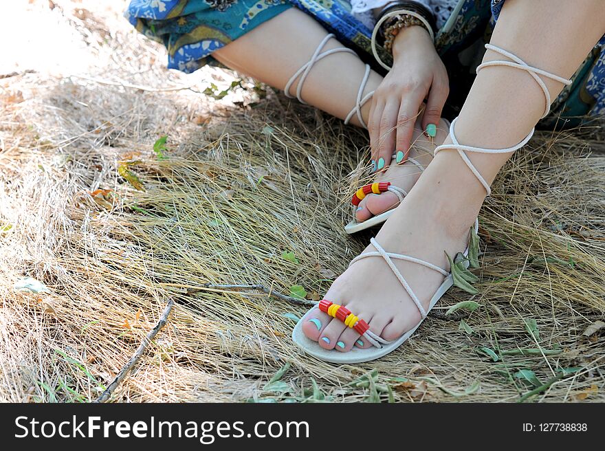 Handcrafted sandals on a woman legs, close up, blue pedicures, indie style, body care concept, sunny outdoor