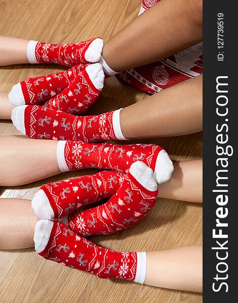 Adults and children legs crossing on the wooden floor with colorful Christmas socks with red and white ornament