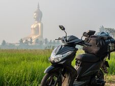 Large Sitting Buddha Above The Palm Trees And Rice Fields With Scooter On Foreground. The Biggest Buddha Of Thailand Royalty Free Stock Photography