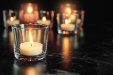 Burning Candle On Table In Darkness, Space For Text Stock Photos
