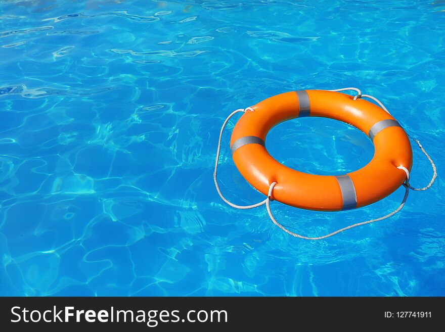 Lifebuoy floating in swimming pool on sunny day