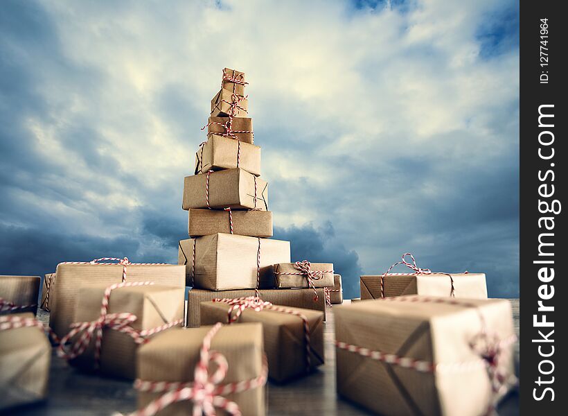 Pile of Christmas gifts wrapped in brown paper against the clou