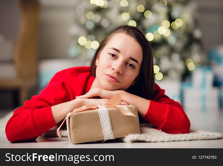 Beautiful happy young woman lying on the floor holding a Christmas present
