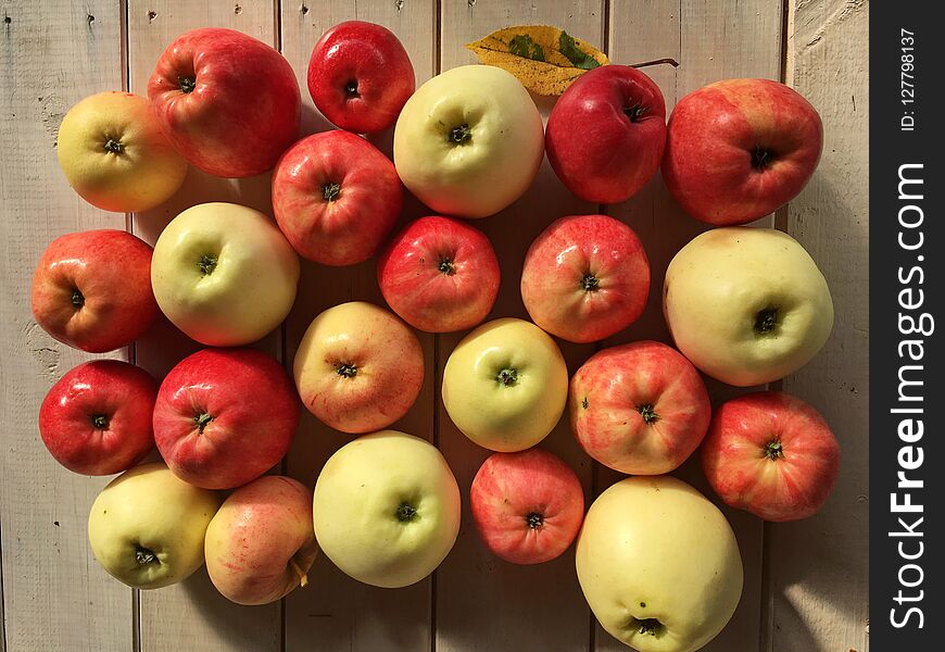 Autumn gifts, set of apples, red and green, juicy, appetizing, shiny peel, on a white wooden table