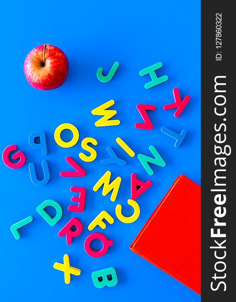 Children learn read concept. Hand hold plastic letters of toy alphabet on blue background top view