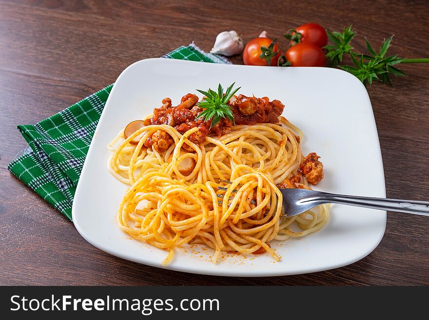 Spaghetti with sauce in the dish on the wooden table