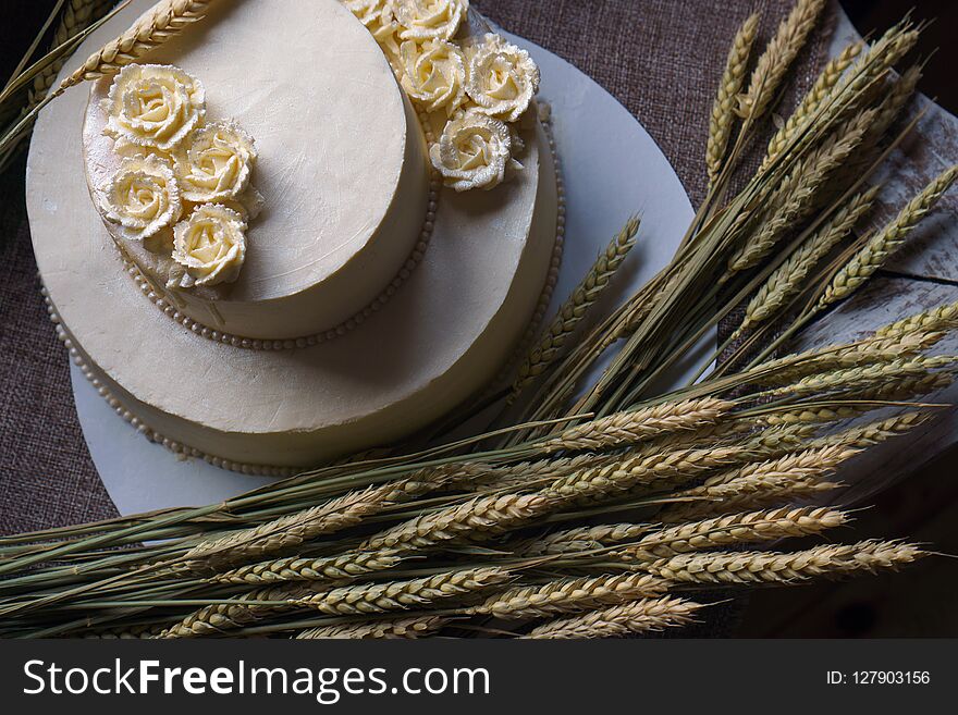 Wedding Cream Cake On Rustic Background. Beautiful Gourmet Tart Decorated With White Roses And Ears Of Wheat.