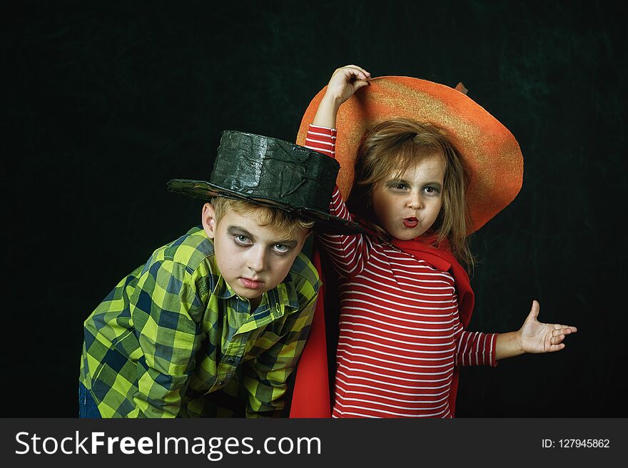 Brother and sister on Halloween. Funny kids in carnival costumes on dark background . Brother and sister on Halloween. Funny kids in carnival costumes on dark background .