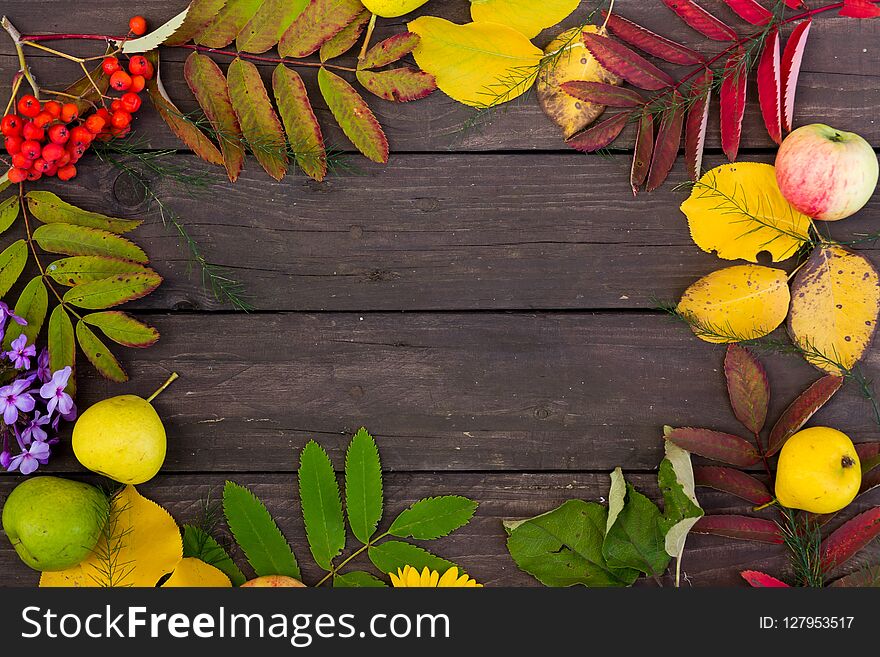 Beautiful frame of colorful autumn leaves, fruits and flowers on brown wooden background, top view. copy space