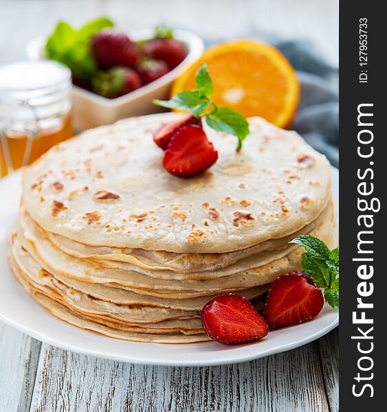 Delicious pancakes with strawberry on white wooden background