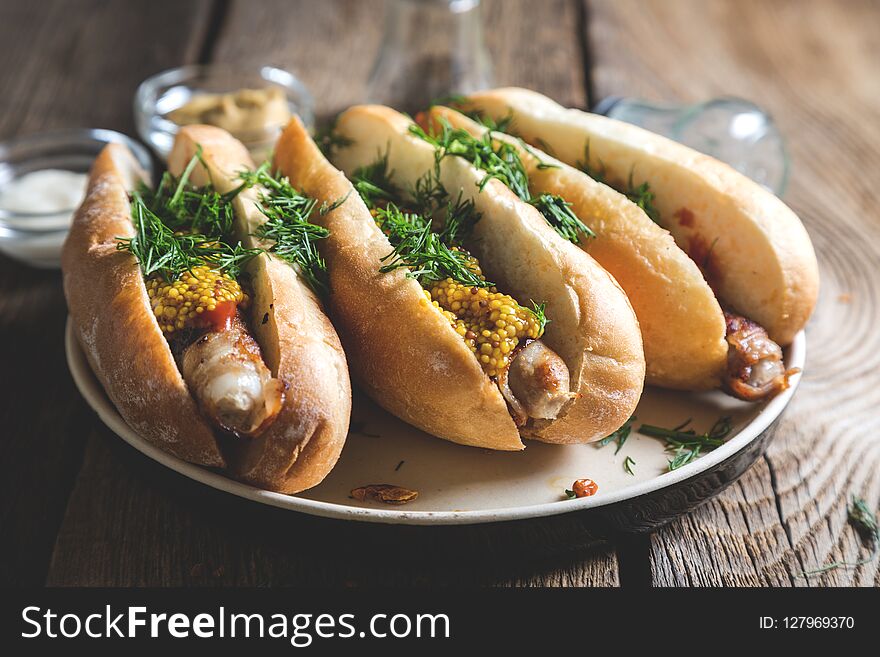 Hot dogs with mustard and chopped dill on wooden table