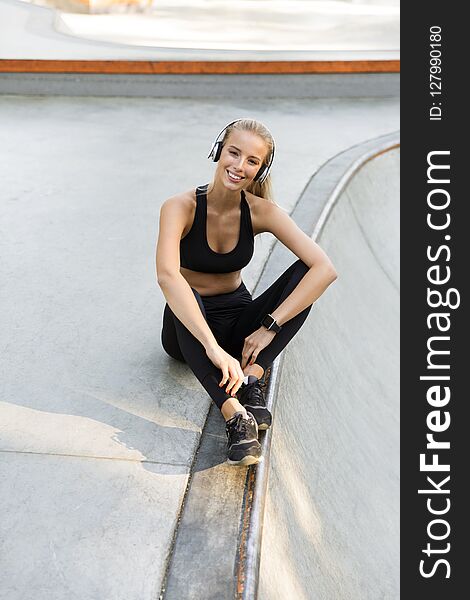 Amazing Happy Young Sports Woman Sitting Outdoors Listening Music.