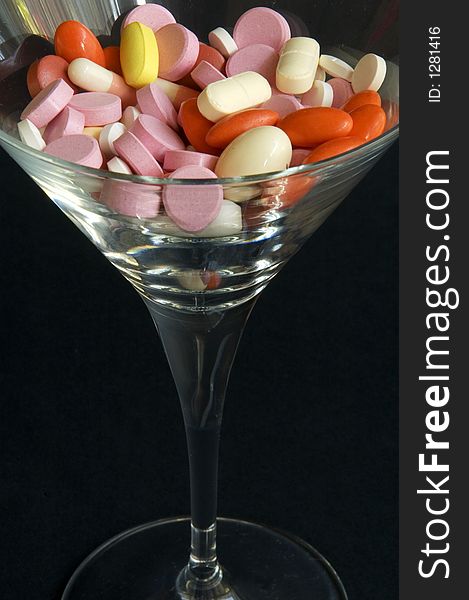 Some colorful pills in wine glasses. Some colorful pills in wine glasses