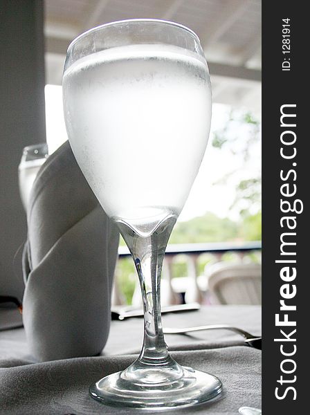 Glass of water on a table, in a restaurant.