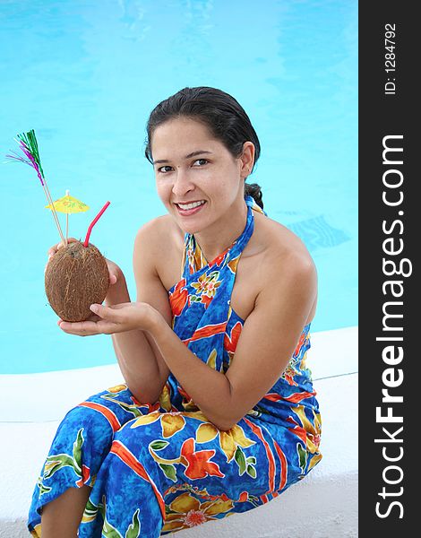 Young woman drinking coconut milk by the water. Young woman drinking coconut milk by the water