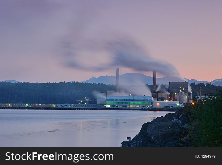 Factory belching out smog from its smokestacks lit by the evening light