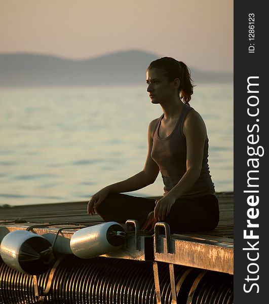 Young woman sitting in lotus pose, sea at the background. Young woman sitting in lotus pose, sea at the background
