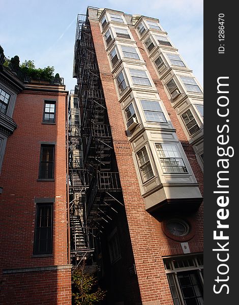 Image of an old tall apartment building in downtown boston showing two rows of bay windows and full fire escape. Image of an old tall apartment building in downtown boston showing two rows of bay windows and full fire escape