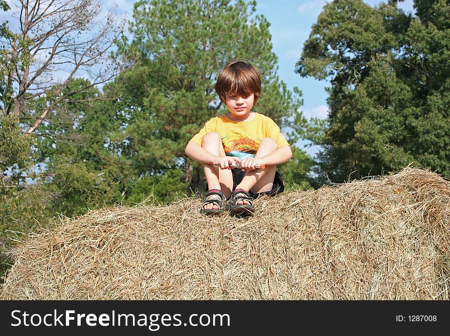 A young boy sitting ona  haybale. A young boy sitting ona  haybale