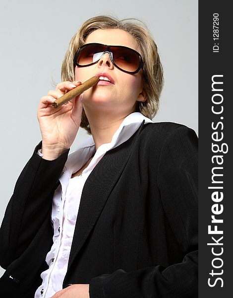 Blond woman smoking a cigar with sunglasses with grey background. Blond woman smoking a cigar with sunglasses with grey background
