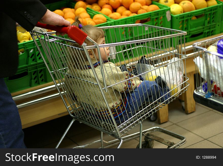 The adult person carries the child in a carriage for products