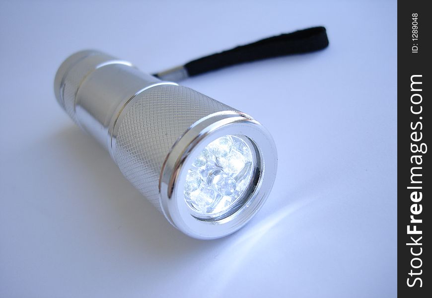 Silver metallic flashlight on blue background