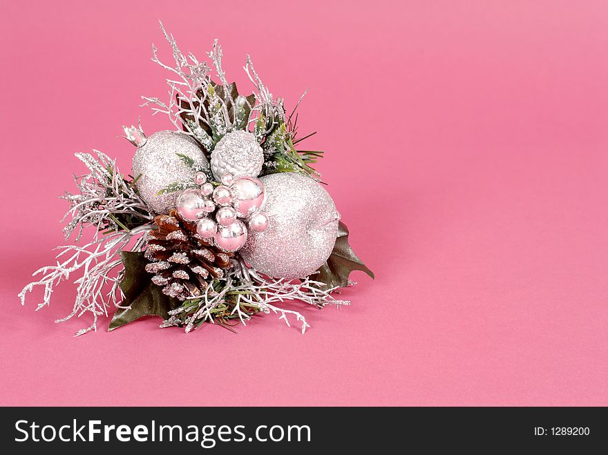 Silver Christmas ornament made of multiple balls, leaves, and pine cone on ruby background